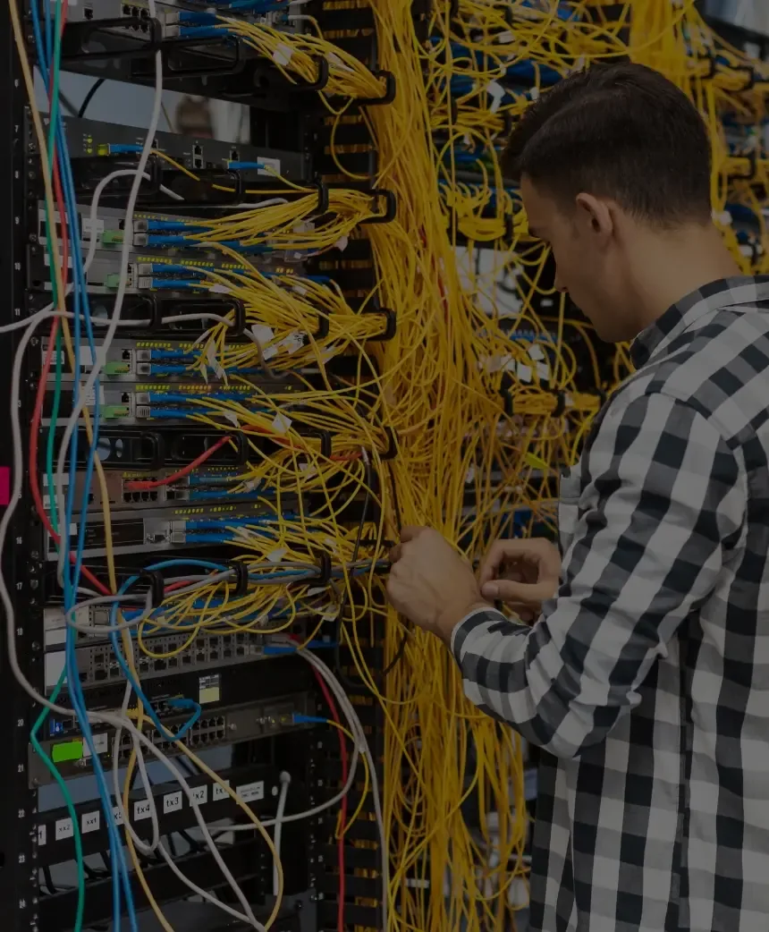 Technician patching fibre and Ethernet cabling in a server cabinet